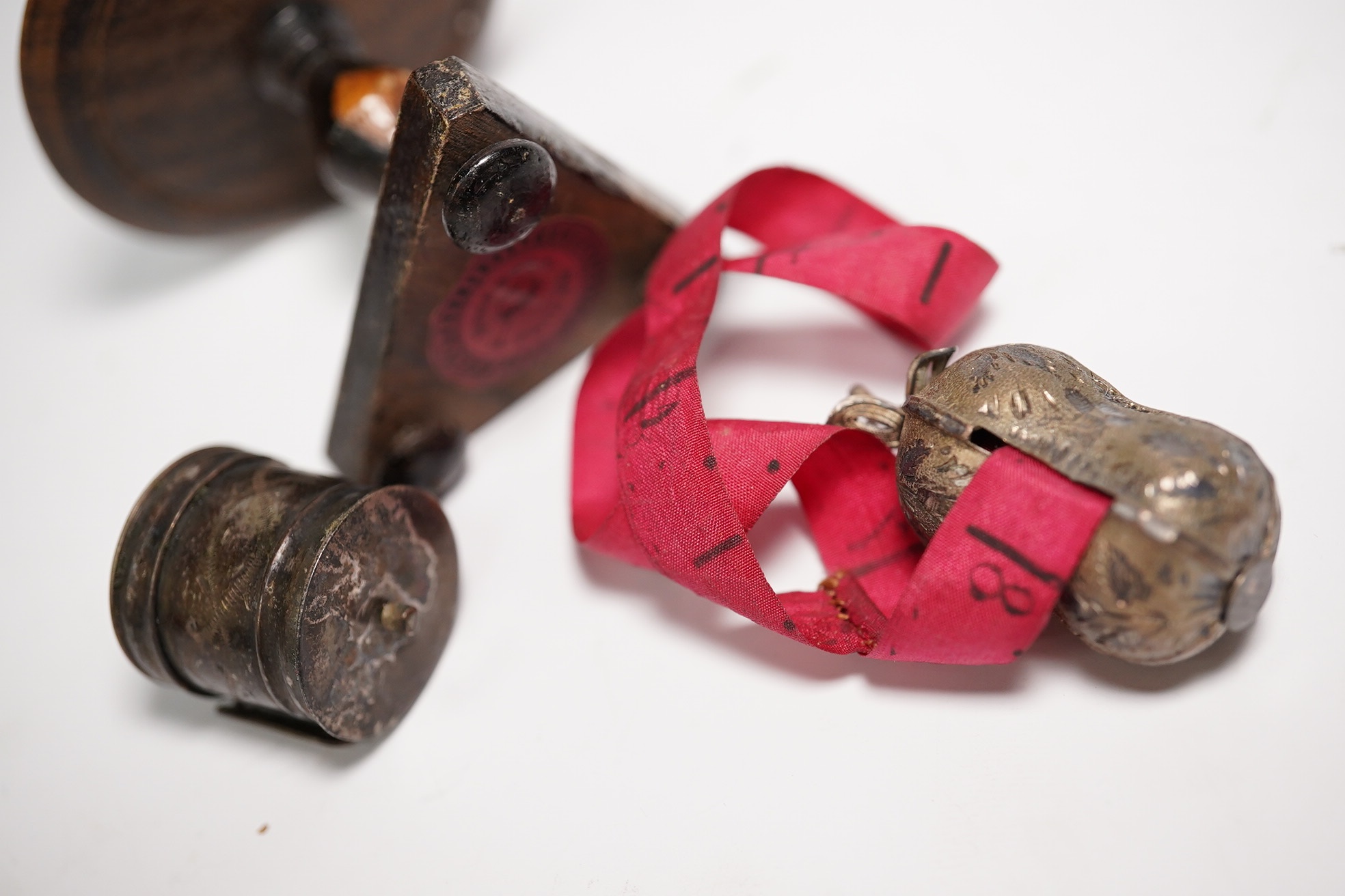 Two early Victorian white metal tape measures and a rosewood miniature 'table' pin cushion. Condition - fair
